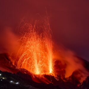 Volcano erupting with glowing lava and smoke at night.